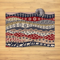 Cat laying on an African rug on a wood floor.