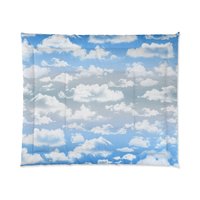 King comforter printed with fluffy white clouds on a blue and gray ombré sky background.
