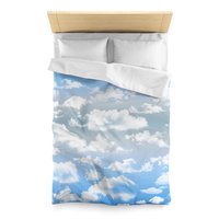 Twin duvet cover printed with fluffy white clouds on a blue and gray ombré sky background.