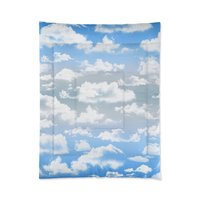 Twin comforter printed with fluffy white clouds on a blue and gray ombré sky background.
