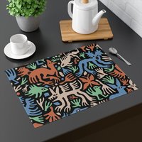 Placemat with Cute folk art of otherworldly dinosaurs, flora and fauna in brown, beige, green and blue on a black background.