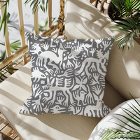 Primitive white hand-drawn animals and plant life. Printed on a gray background. Pillow on a balcony chair.