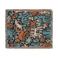 woven blanket with Modern folk art of otherworldly dinosaurs, flora and fauna in brown, beige, green and blue on a black background. 