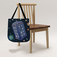 The Tardis floating in the solar system tote bag hanging on the shoulder of a woman at a restaurant counter.