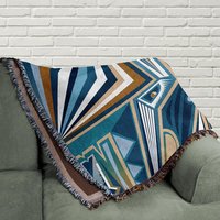 Modern Cubist Woven Blanket – Abstract Art Throw in Blue and Brown folded on a couch.