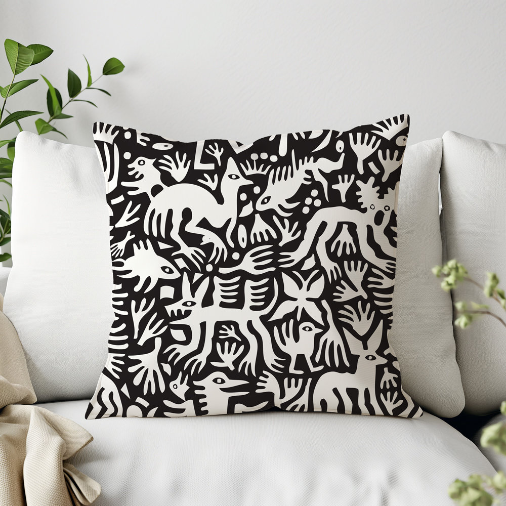 Primitive white hand-drawn animals and plant life. Printed on a black background. Pillow on a couch.