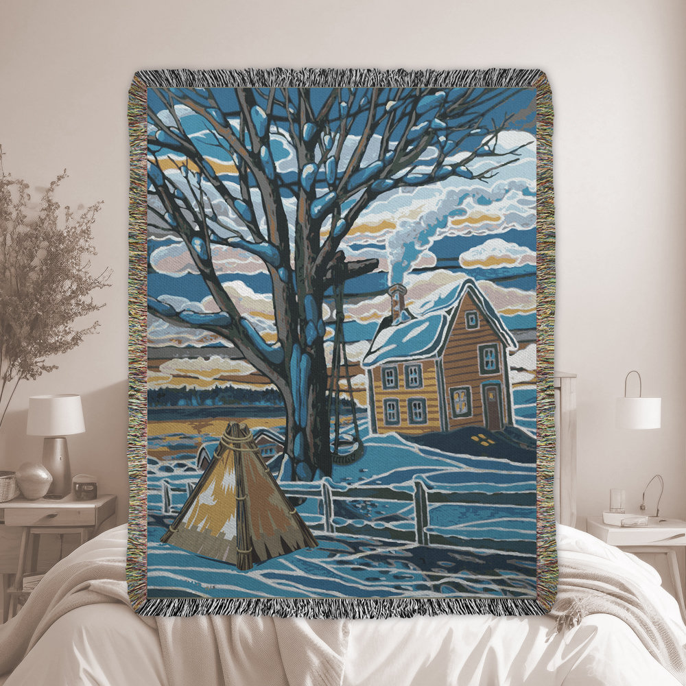 Woven blanket of a Canadian winter landscape scene with trees, a country home, and a tipi outside the fenced backyard in blues, grays and browns.