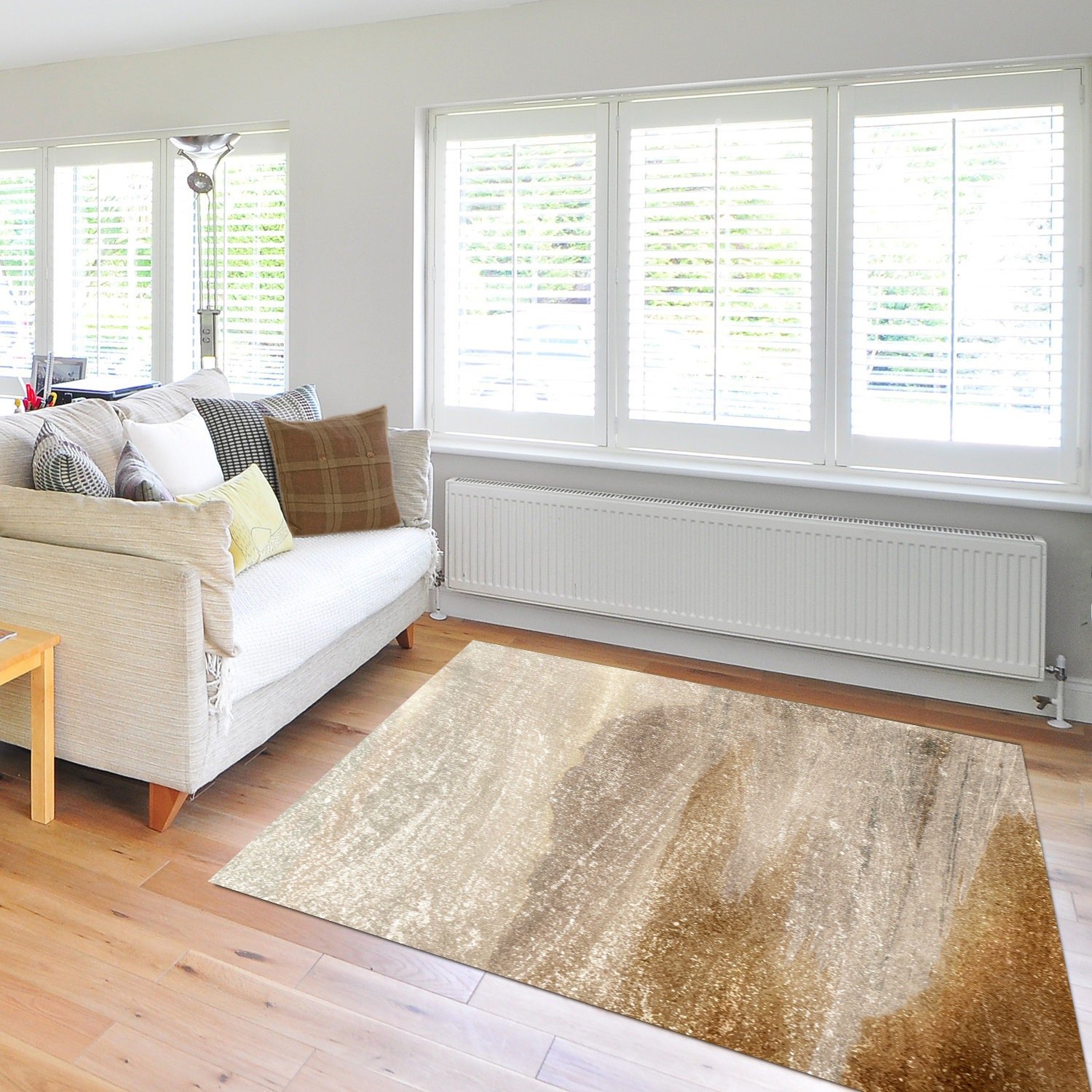Neutral area rug with an abstract coastal haze design in taupe, beige, and soft grey tones styled on a wood floor in a modern minimalist apartment.