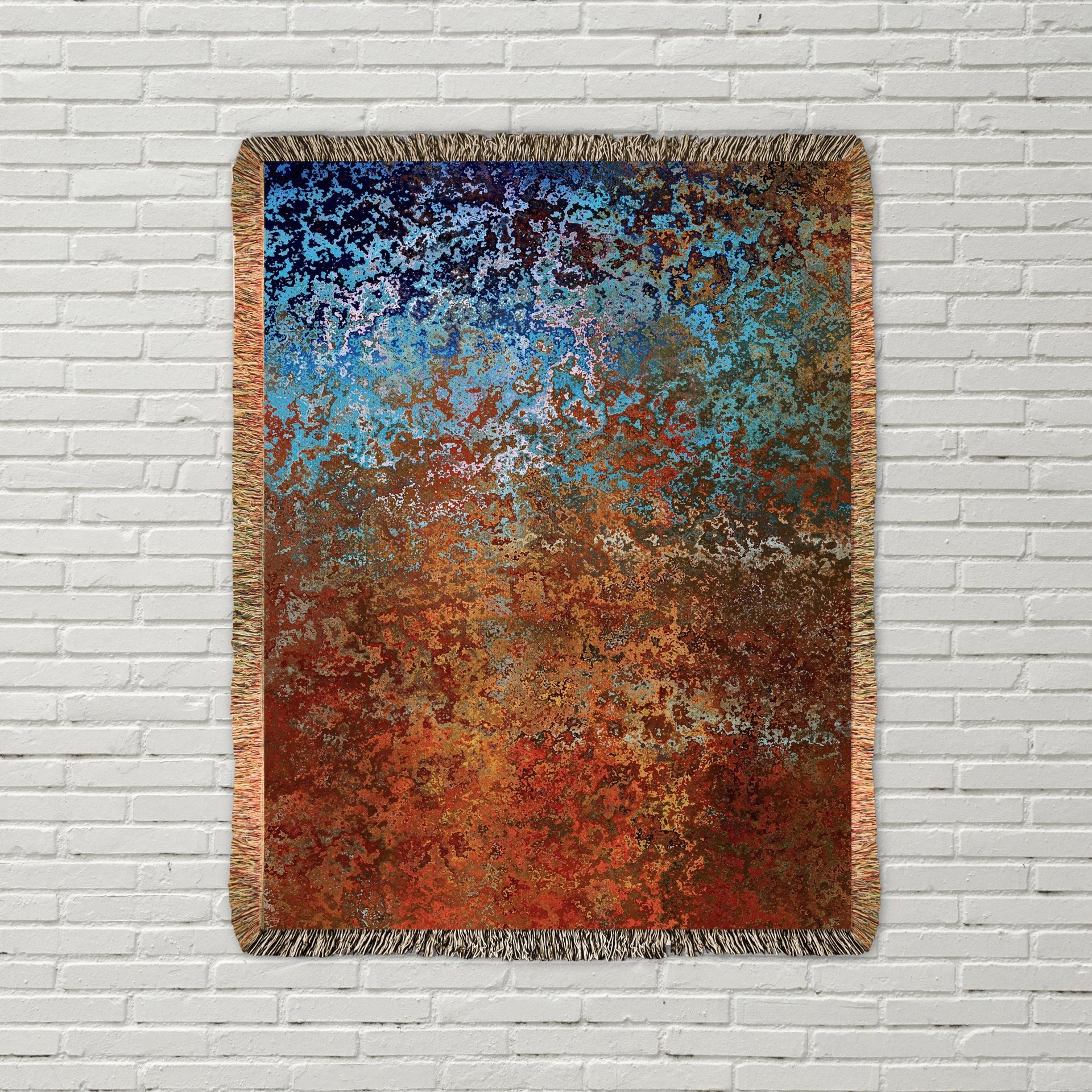 Abstract Ombré Woven Blanket in Southwestern Colors hanging on a white brick wall.