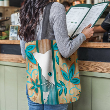 Mama Cat and Kitten Woven Tapestry Bag hanging on the shoulder of a young woman at a restaurant counter while she reads a menu.