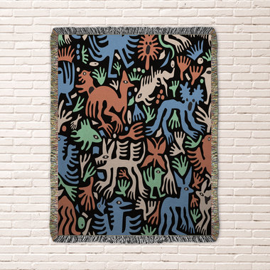woven blanket with Modern folk art of otherworldly dinosaurs, flora and fauna in brown, beige, green and blue on a black background. 